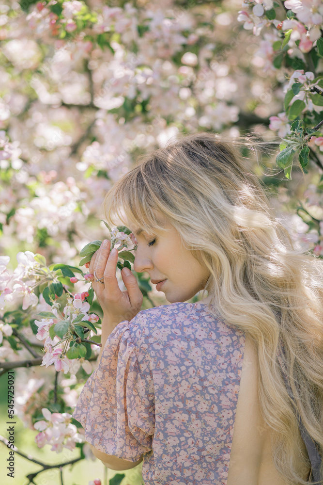 Portrait of a beautiful woman who smells flowers, blooming apple orchard, long blond hair, spring time, standing back, book cover Portrait of a beautiful woman who smells flowers, blooming apple orchard, long blond hair, spring time, standing back, book cover