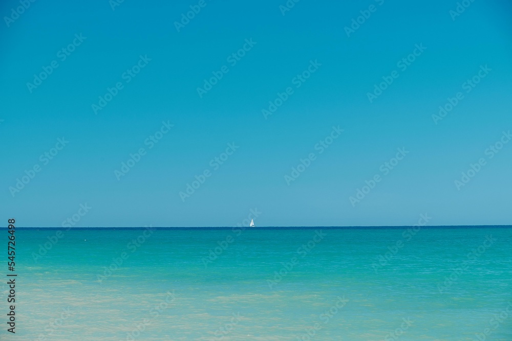 Minimalistic seascape with a sailboat in the horizon