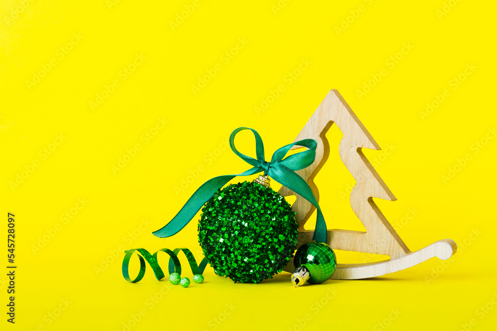 Christmas ball with decorative wooden tree on colored background. decoration bauble with ribbon bow with copy space