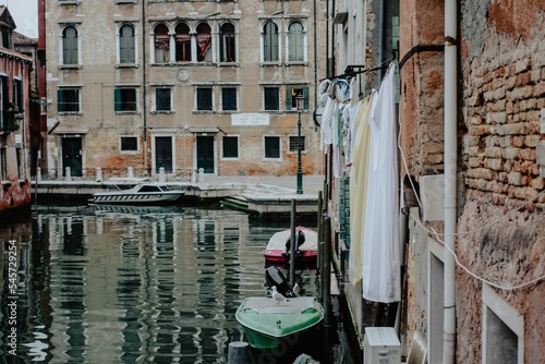 Beautiful shot of a residential building with hung laundry and boats on a water photo