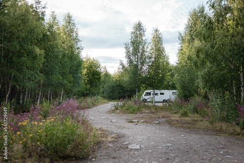 Rocky road in a forest with a motorhome in the background under a cloudy sky © Torbjorn Lagerwall/Wirestock Creators