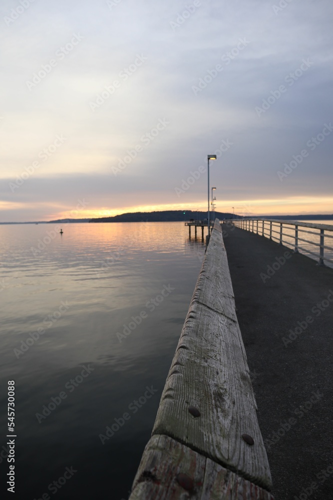 Beautiful sunrise scene over the sea with a long empty pier lit by street lights