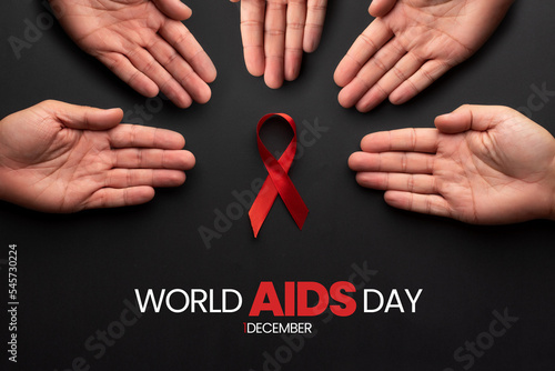 Set of hands encircling a red ribbon symbolizing World AIDS Day. December 1st, day of the fight against hiv disease. Supporting the sick photo