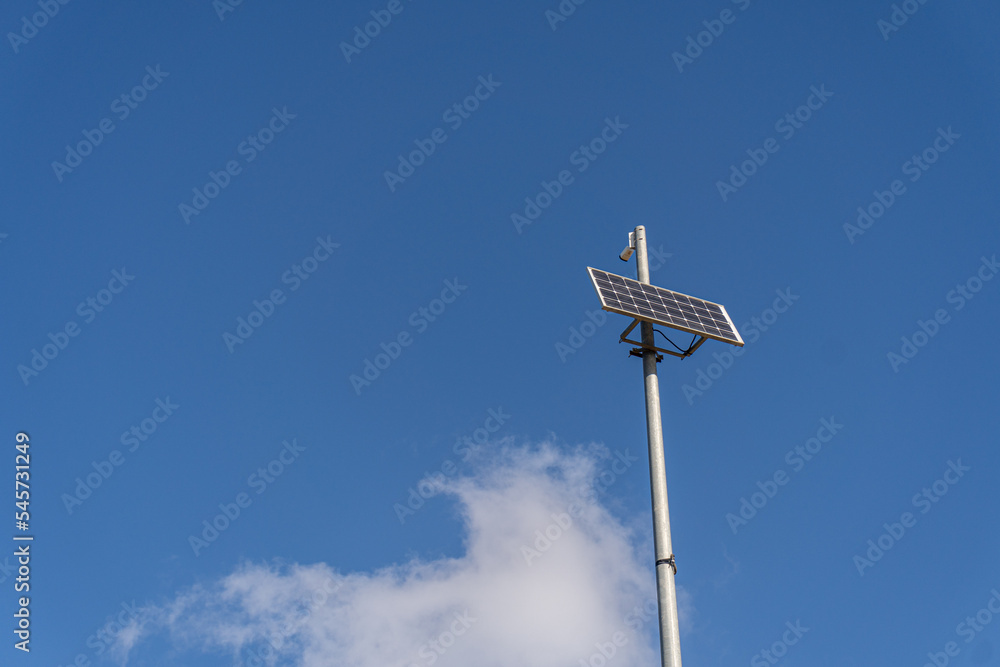 Small solar panel installed on a metal pole, against a blue cloudy sky Small solar panel installed on a metal pole, against a blue cloudy sky
