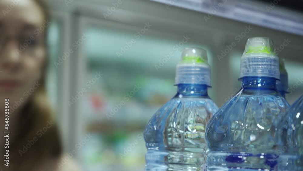 Young woman buying bottle of mineral water in supermarket Young woman buying bottle of mineral water in supermarket