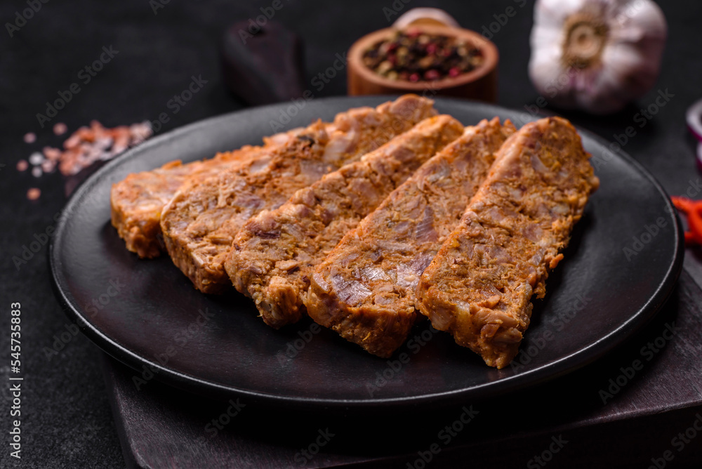 Tasty meat brawn or roll on a wooden cutting board with spices and herbs Tasty meat brawn or roll on a wooden cutting board with spices and herbs