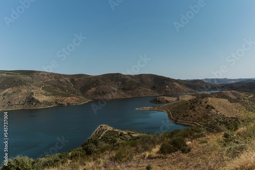 Landscape of Miradouro de Sao Lourenco green hills by water under blue sky in Portugal