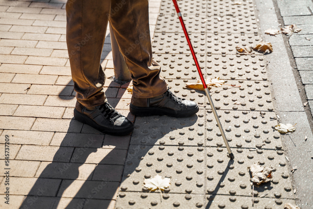 Close-up of a blind man with a walking stick. Detects tactile tiles for self-orientation while moving through the streets of the city Close-up of a blind man with a walking stick. Detects tactile tiles for self-orientation while moving through the streets of the city