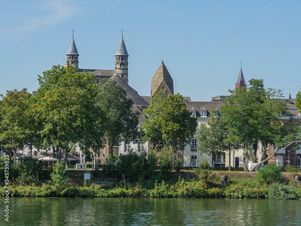 Beautiful view of the Maas river surrounded by trees and old buildings in Maastricht, Netherlands.