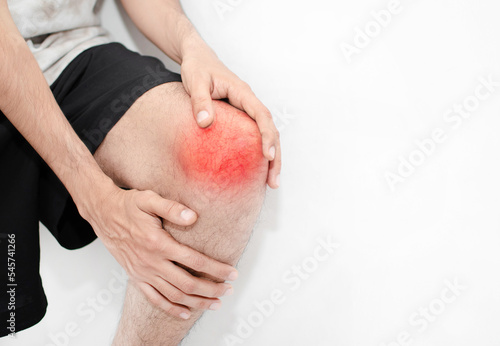Rodilla lastimada y roja por una lesión musculoesqueletica de un joven hombre caucasico sobre un fondo blanco 
