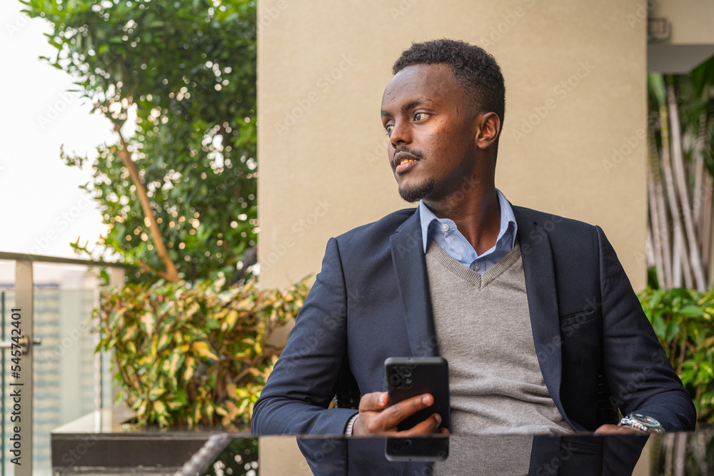 Portrait of handsome black African businessman using phone while thinking Portrait of handsome black African businessman using phone while thinking