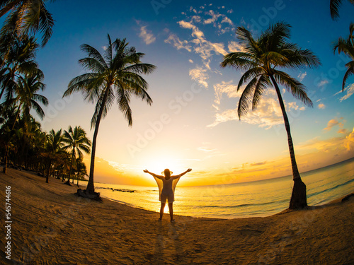 Billede på lærred Woman walking on sunny, tropical beach at daybreak