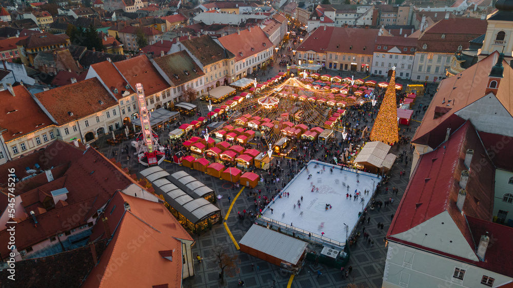 Aerial photography of the Christmas Fair in Sibiu shot from a drone at a higher altitude with camera tilted downwards for a top view shot. The still was taken at sunset, with city lights turned on.