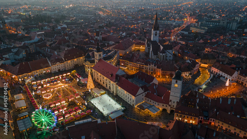 Landscape photography of Sibiu city center with the Christmas Fair, shot from a drone at higher altitude, at sunset with the city lightning on. Birds eye view over cityscape of Sibiu, Romania.