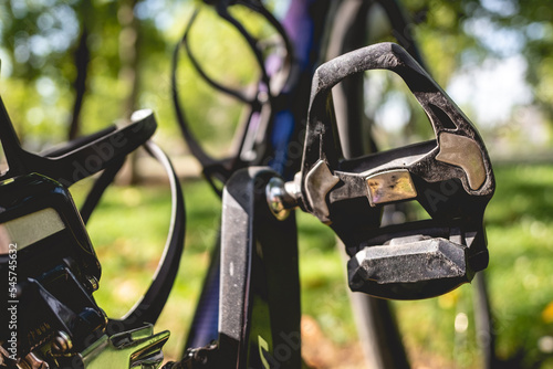 Details of one pedal and crank of a pro bike in the park in a sunny day