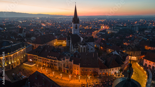 Birds eye view over historic city center of Sibiu, Romania at sunset. Aerial photography was shot from a drone at sunset with the Council Tower and a beautiful cityscape in view. 