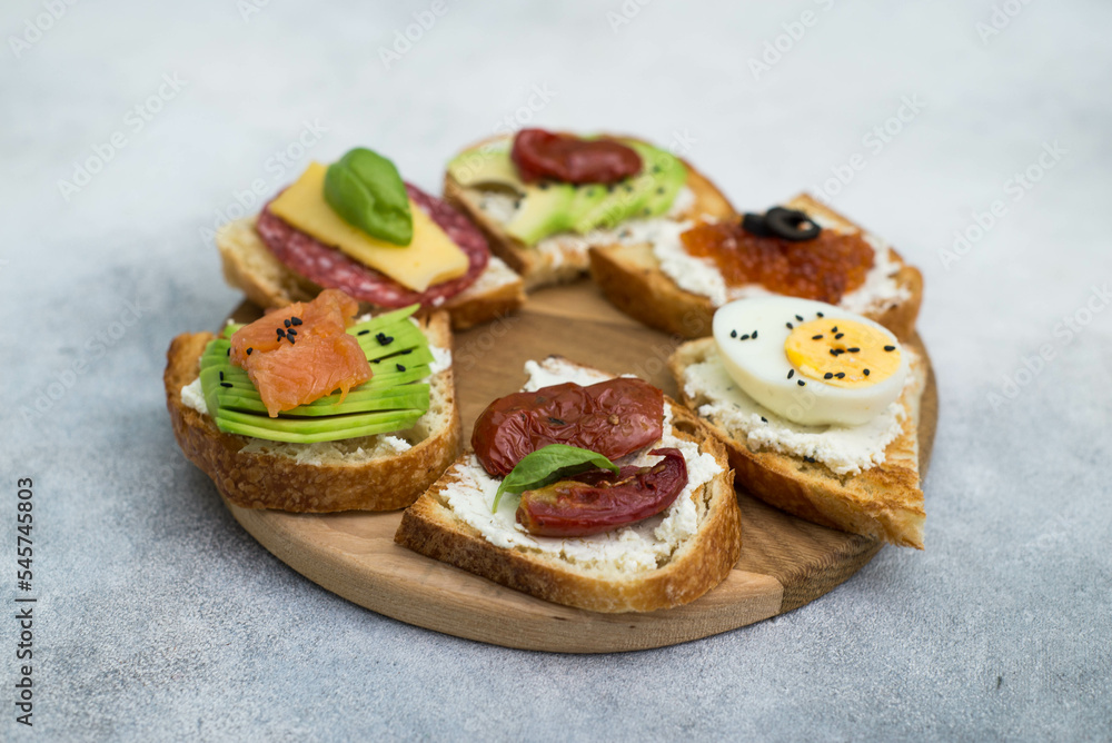 Variety of tapas sandwiches for aperetif on wooden on gray background. Top view.