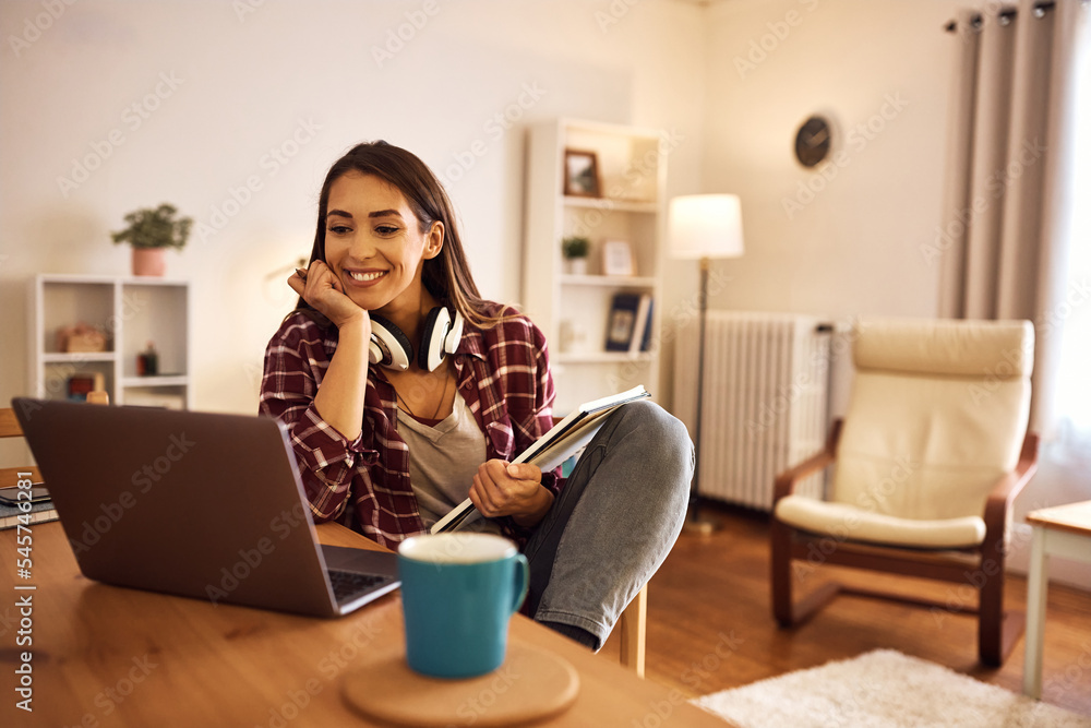 Happy female student having online class over laptop at home. Happy female student having online class over laptop at home.