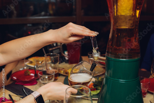 The male bartender pouring beer into a glass close-up. Street food. A glass with cold beer in the bartender s hands. photo