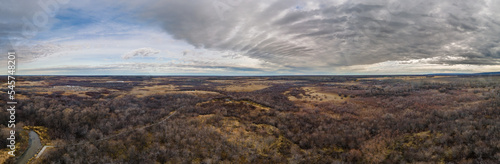 Aerial panorama of a dry prairie setting with a small stream under a sky with interesting clouds 