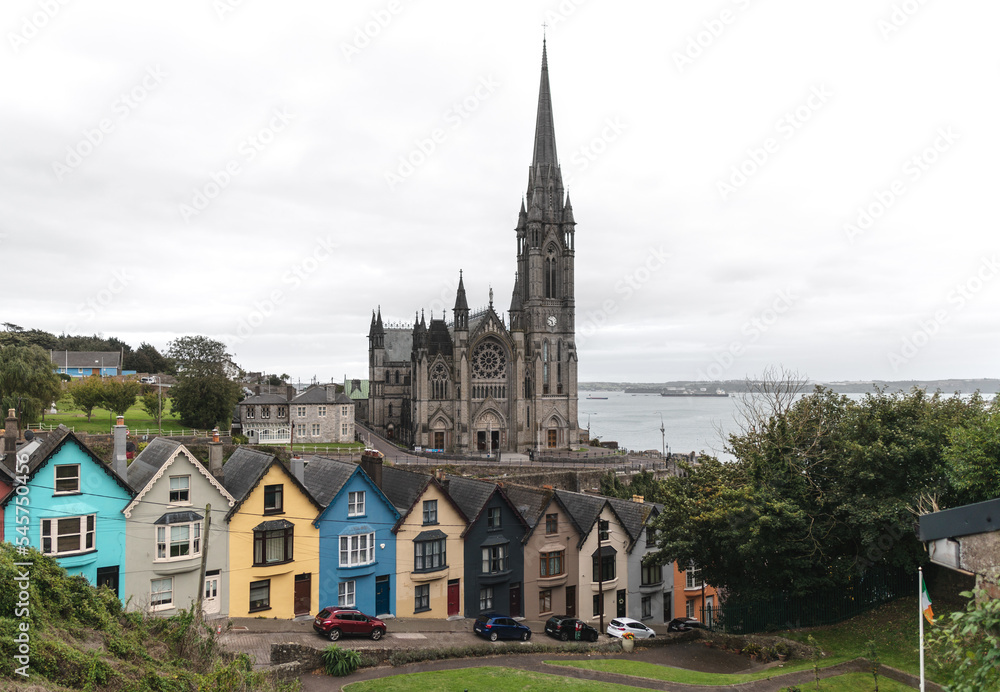 Colorful row of houses with towering cathedral in background in the port town of Cobh, County Cork, Ireland Colorful row of houses with towering cathedral in background in the port town of Cobh, County Cork, Ireland