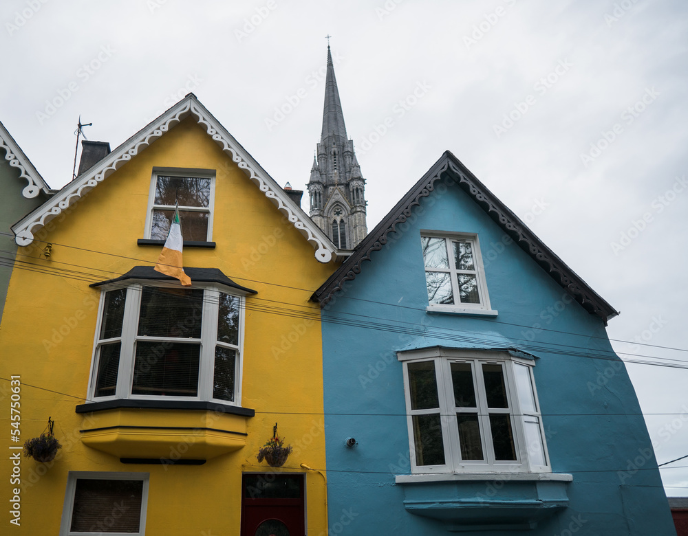 Colorful row of houses with towering cathedral in background in the port town of Cobh, County Cork, Ireland