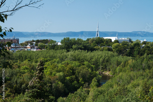 Church of Saint Patrice parish with its leaning bell tower in Riviere-du-loup, Quebecc with Saint Lawrence river and mountain seen from the park. Eglise de Rivière du Loup