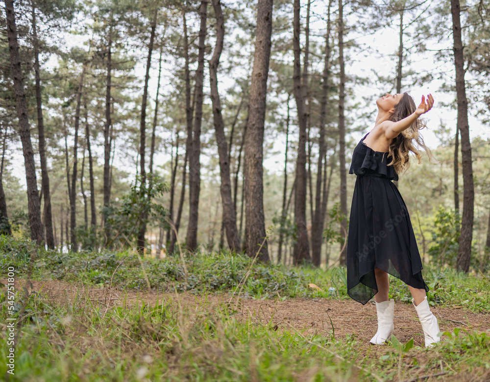 Blonde woman looking sky in forest with open arms. She admires nature. Blonde woman looking sky in forest with open arms. She admires nature.