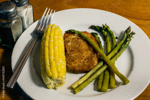 baked cod fillet served with asparagu and corn photo