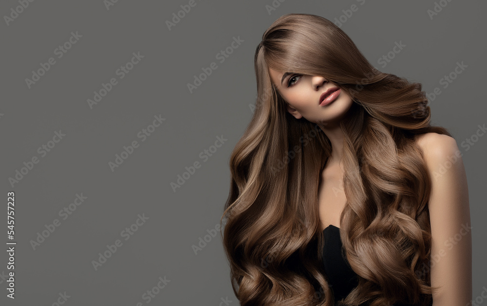 Beautiful woman with long wavy hair. Gray background. Beautiful woman with long wavy hair. Gray background.