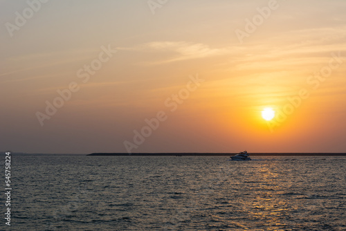 Amazing sunset in Dubai with colourful sky, calm sea and a small yacht 