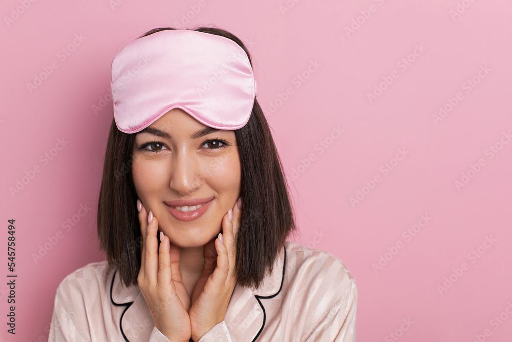 Porter is a beautiful young woman of oriental appearance standing in pink pajamas and a sleeping mask in the bedroom. suffers from insomnia.