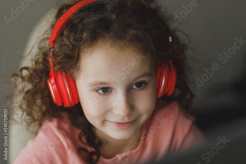 A girl with headphones is studying at the computer