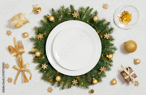 Christmas empty table setting with golden accessories on gray background. View from above. Space for text.
