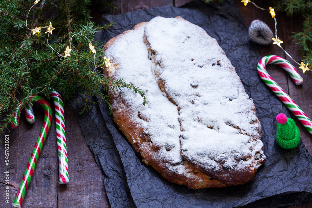 Christmas stollen with dried fruits, nuts and spices, Christmas decorations on a dark wooden background. Rustic style.