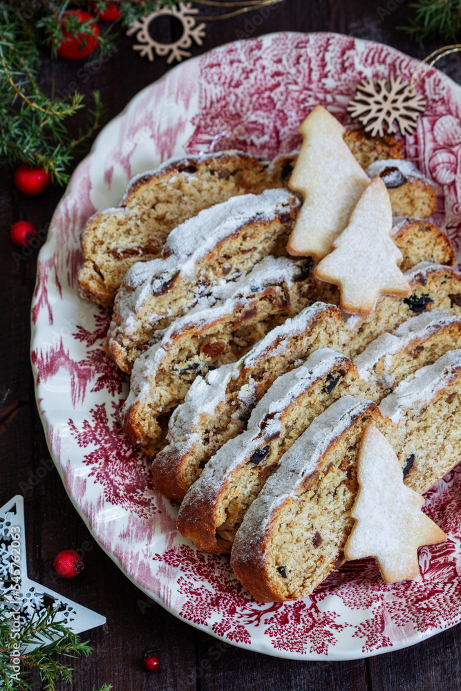 Christmas stollen with dried fruits, nuts and spices, Christmas decorations on a dark wooden background. Rustic style.