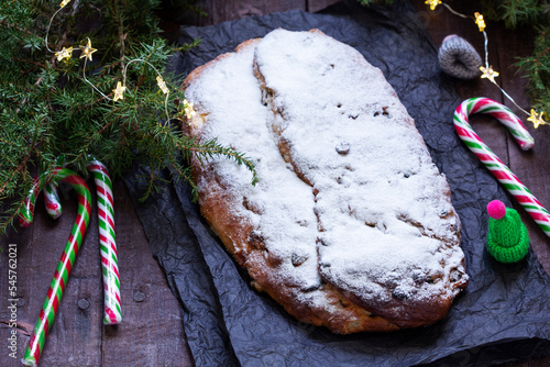 Christmas stollen with dried fruits, nuts and spices, Christmas decorations on a dark wooden background. Rustic style.