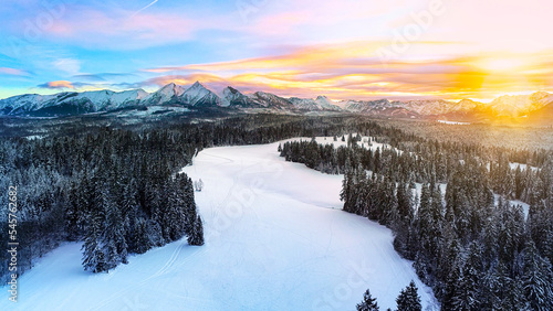 Snow capped mountains in the winter, aerial view. Aerial panorama of winter mountain landscape and colorful sunset sky. Tatra high mountains and magical unspoiled scenery.