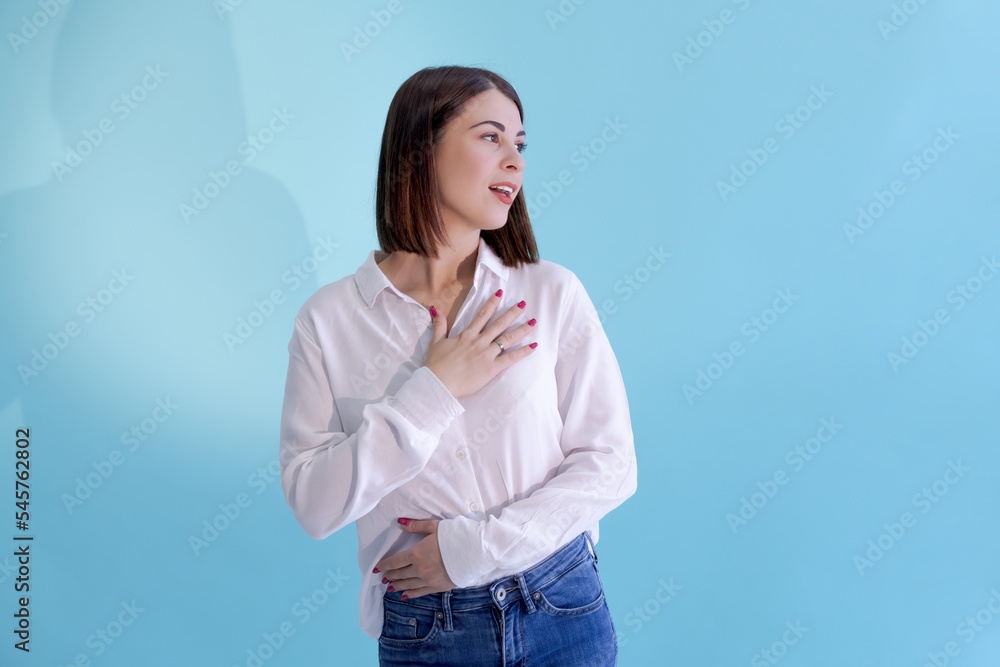 Portrait of beautiful smiling brunette caucasian woman wearing white shirt. Blue background. Selective focus. People theme. Portrait of beautiful smiling brunette caucasian woman wearing white shirt. Blue background. Selective focus. People theme.