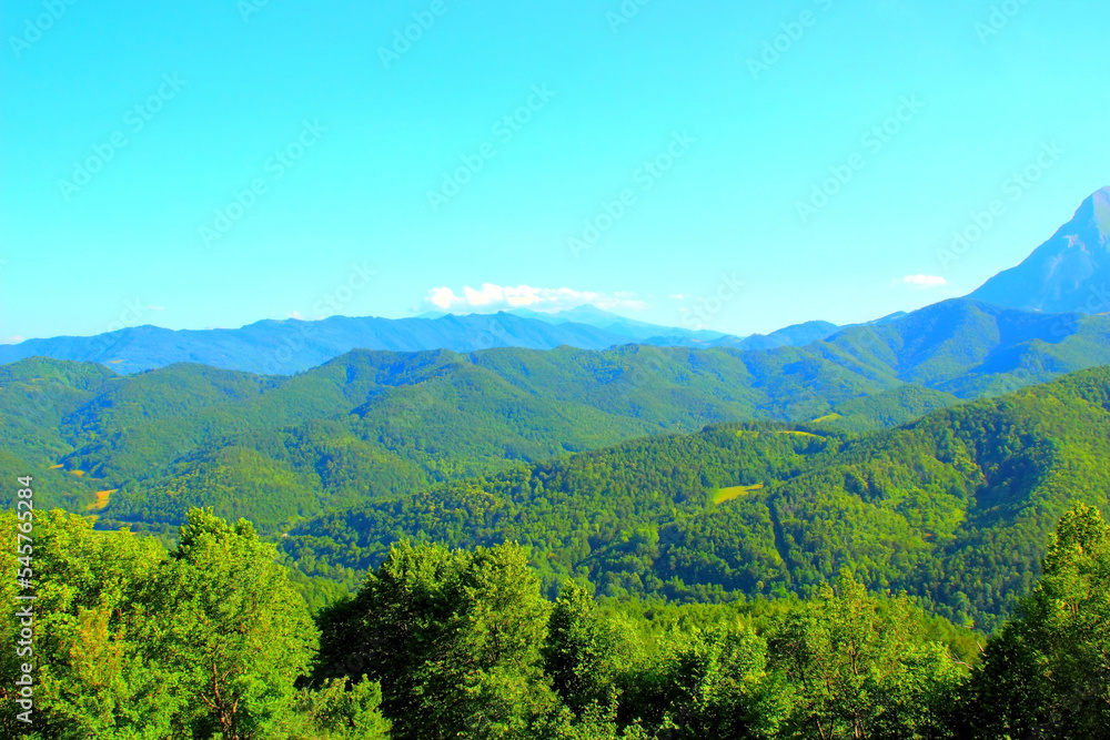 Riveting scenery in Montemonaco with many ridges of edged green hills dominating the landscape and a very tall slice of Sibillini mountains on the right in the background under an anodyne sky