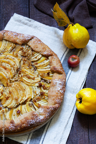 Open pie stuffed with apples, quince and nuts on a wooden background. Rustic style.