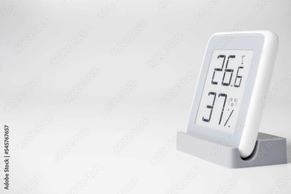 A home weather station standing on a white background is a modern device with a screen showing the temperature and humidity in the room. Side view, copy space A home weather station standing on a white background is a modern device with a screen showing the temperature and humidity in the room. Side view, copy space