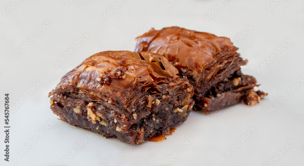 Chocolate baklava on a white plate. Turkish style chocolate baklava presentation and service. Horizontal view. Chocolate baklava on a white plate. Turkish style chocolate baklava presentation and service. Horizontal view.
