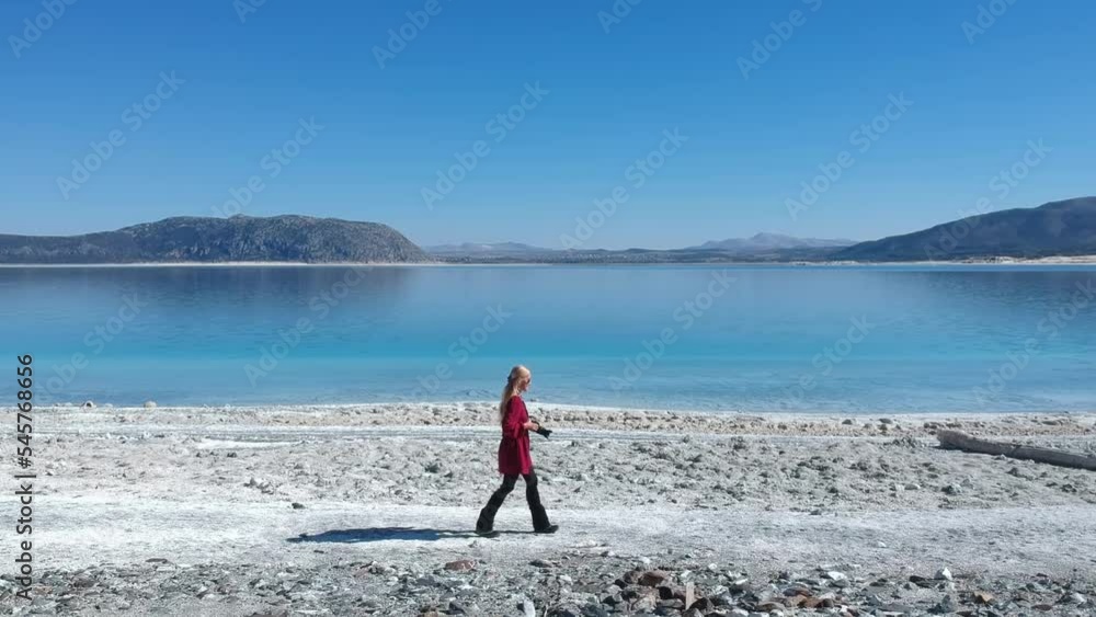 Stockvideo drone footage of a blonde woman walking on the white sands ...