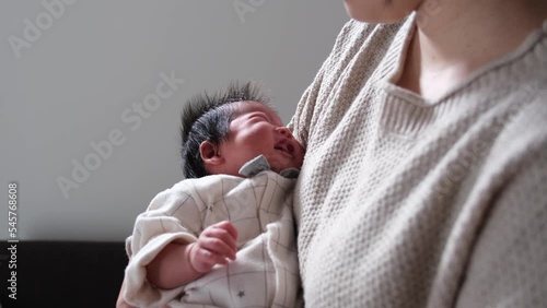大泣きしている産後1か月0歳の新生児を母親が抱っこしている様子の動画 photo