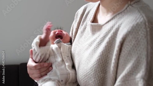 大泣きしている産後1か月0歳の新生児を母親が抱っこして揺らしながらあやしている様子を撮影した動画 photo