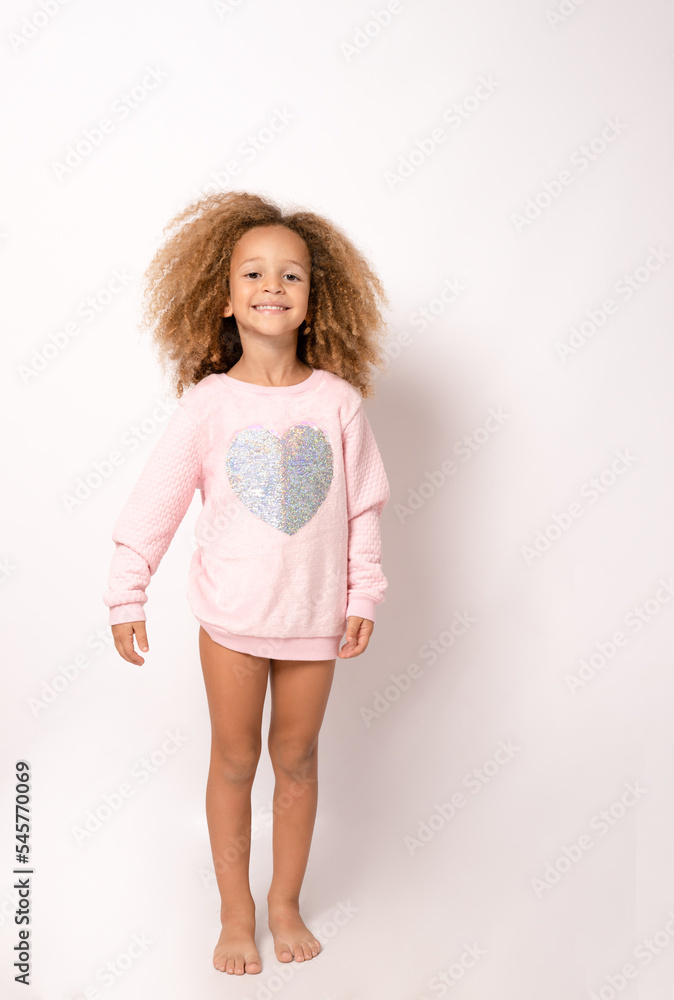 Happy cute child girl with curly hair in pink dress standing isolated over white background. Happy cute child girl with curly hair in pink dress standing isolated over white background.