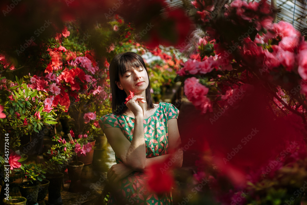 Beautiful brunette in a garden of azaleas in a green dress