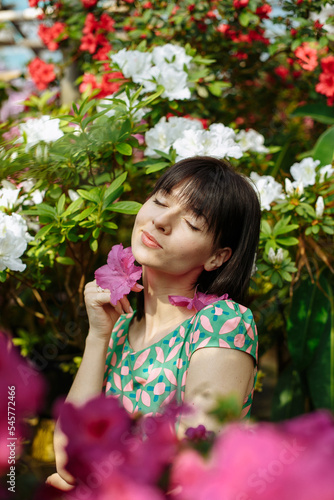 Beautiful brunette in a garden of azaleas in a green dress