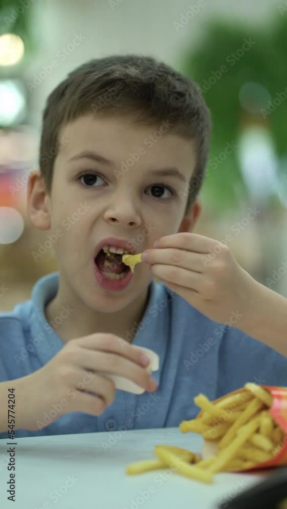 boy eating french fries with cheese sauce. boy eating french fries with cheese sauce.